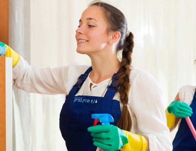 Positive young professional cleaners woman washing apartment with rag and mop